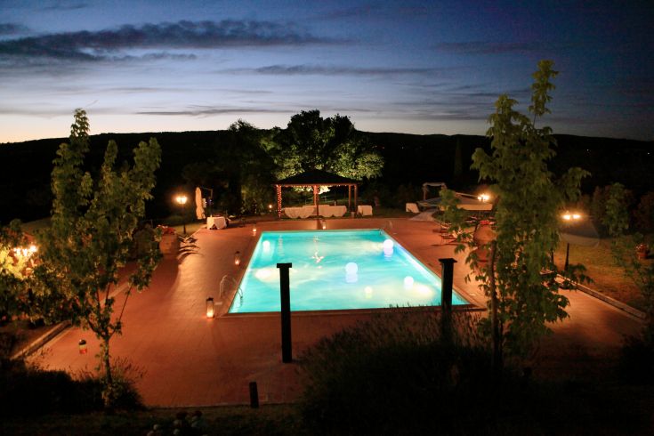 Night view of the illuminated pool at Tenuta di Corbara, surrounded by Umbrian landscapes.