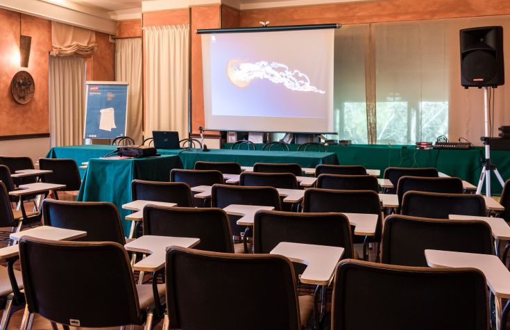 Spazio per incontri situato all'interno di un edificio, arredato per ospitare eventi e presentazioni.