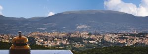 Scena che mostra Perugia e le colline vicine, con un campanello all'ingresso dell'hotel.
