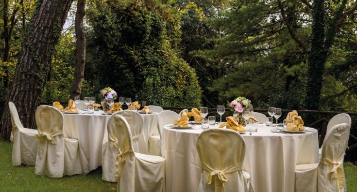 Accogliente allestimento per un pranzo all'aperto, circondato da alberi e piante.