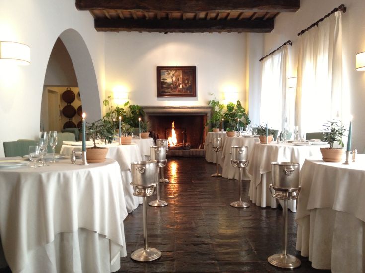 A cozy restaurant with neatly arranged tables and a lit fireplace, creating a warm and inviting atmosphere.