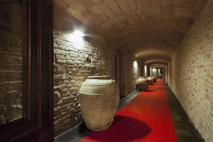 A corridor with red flooring and ceramic vases, illuminated by warm lights.