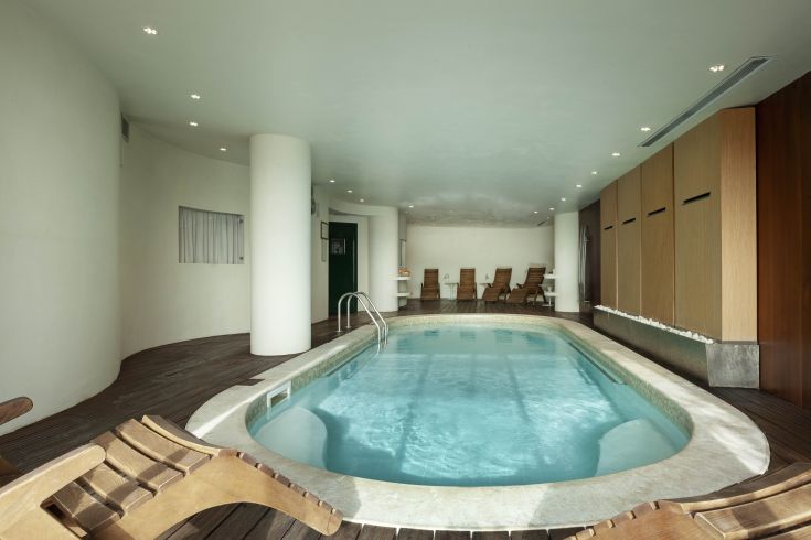 Inside a swimming pool area featuring a relaxation zone with wooden loungers, bright and cozy atmosphere.