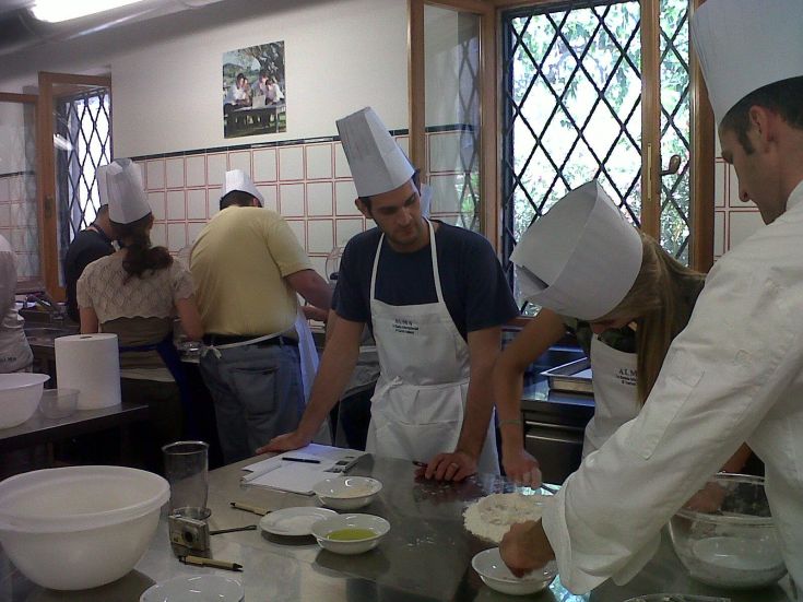A group of cooking enthusiasts collaborates in a workshop to prepare dishes with fresh ingredients.