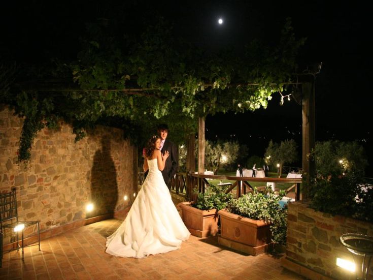 A wedding takes place in a well-lit garden under the moonlight. The atmosphere is warm and inviting.