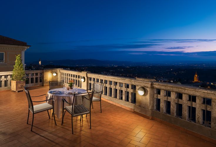 Una terrazza serale con atmosfera accogliente e panorama sulla zona circostante, ideale per una cena tranquilla.