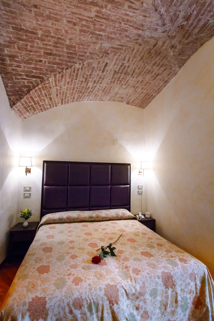A neat room with brick arch ceilings and floral decorations on a bed.