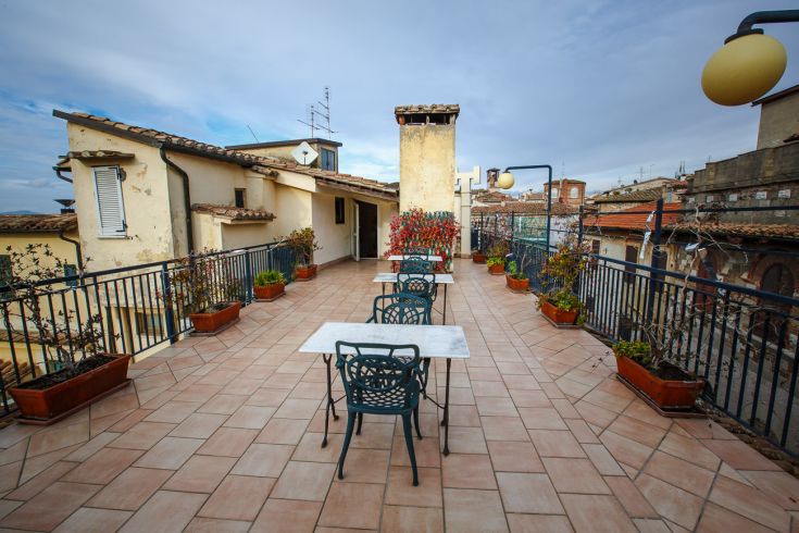 Simple rooftop with tables and plants, overlooking the center of an Umbrian city.