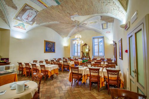 Innenraum eines Restaurants mit dekorierter Decke und ordentlich gedeckten Tischen.