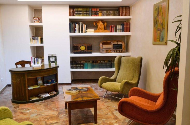 Ambiente confortevole con librerie e divani dai colori vivaci, perfetto per letture tranquille.