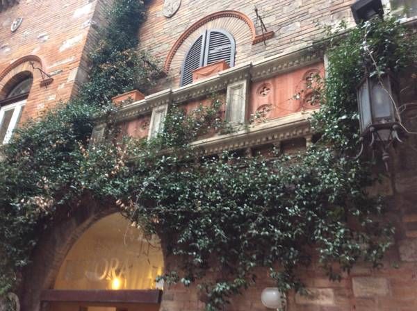 Un edificio nel centro storico con un cortile coperto di edera e camere in stile classico.