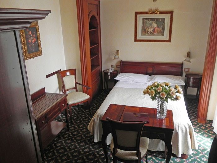 Camera semplice con mobili in legno e qualche decorazione d'epoca, adatta per un soggiorno tranquillo.