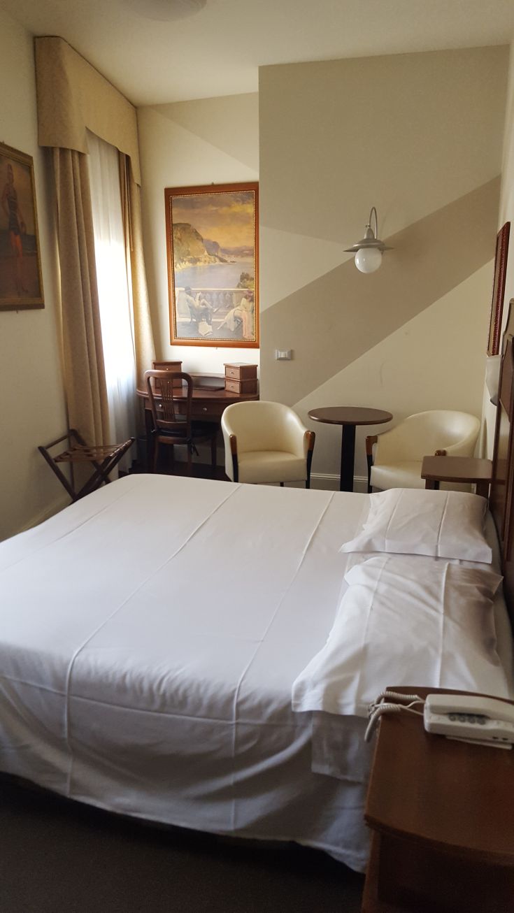 Camera semplice con arredi in stile classico e tonalità neutre, ideale per un soggiorno confortevole.