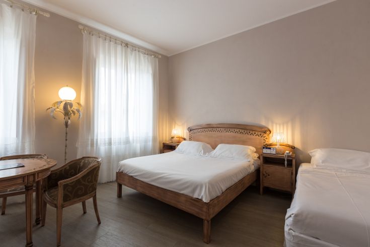 Stanza di un hotel con mobili semplici e luminosità naturale, adatta per un soggiorno confortevole.