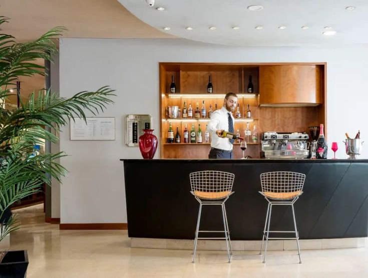 Un barman prepara cocktail in un bar elegante, con arredi contemporanei e un'atmosfera accogliente.