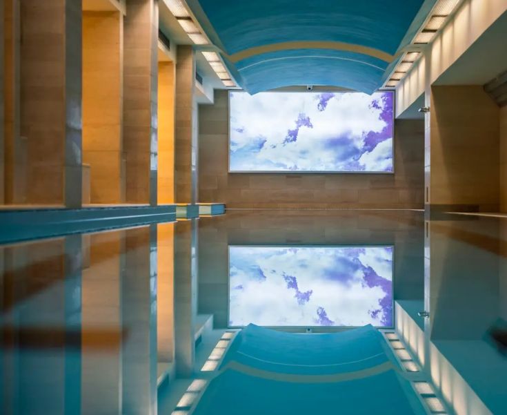 Piscina immersa in un'area tranquilla, con luce naturale che si riflette nell'acqua, perfetta per momenti di relax.