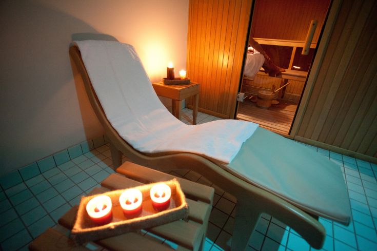 A relaxation area featuring deck chairs, scented candles, and a sauna, perfect for wellness moments.