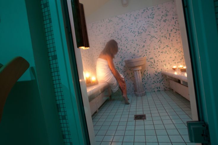 A relaxing moment in a simple sauna, illuminated by soft lights and featuring subtly arranged colored tiles.