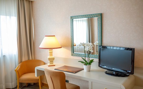 Simple and tidy hotel room with a lamp, TV, and modest decorations, perfect for a comfortable stay.