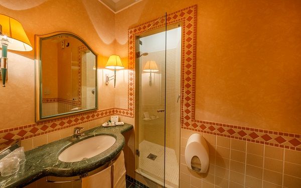 Elegant bathroom with decorative tiles, marble sink, and glass-walled shower.