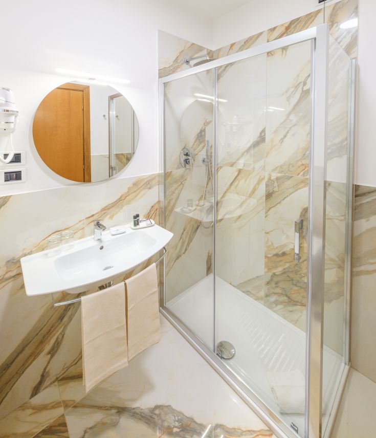 Modern bathroom with shower and sink, enhanced by marble details for a refined atmosphere.