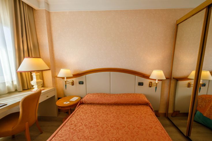 Simple hotel room with modest decor and warm tones, perfect for a comfortable stay.