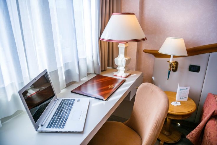 Simple workspace featuring a table, laptop, and lamps, perfect for a relaxing environment.