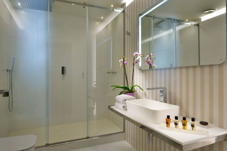 A modern bathroom with a glass shower and simple floral decorations. A comfortable and well-maintained space.