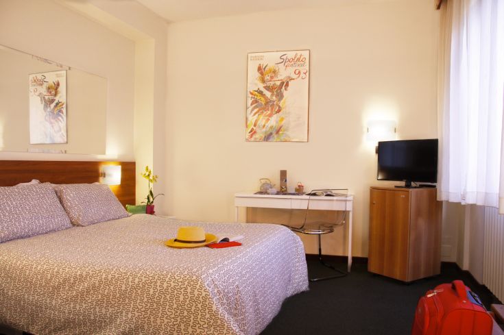 Gemütliches Hotelzimmer mit Doppelbett, warmem Licht und einfacher Einrichtung.