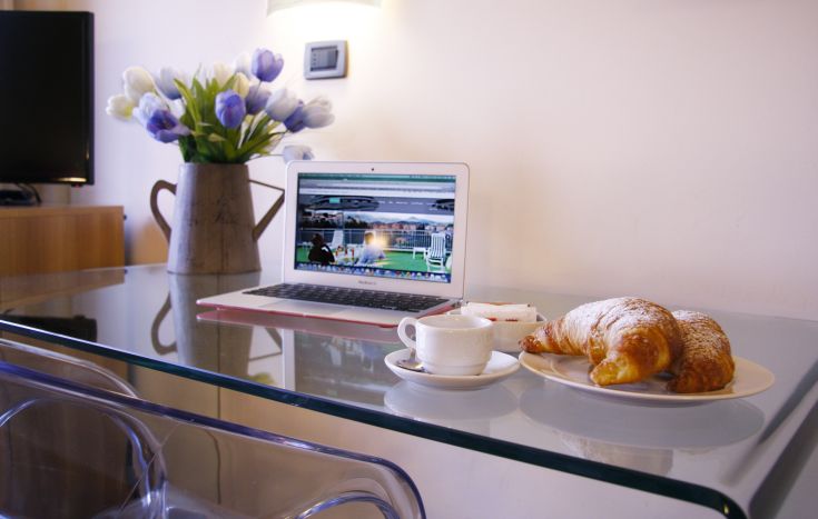 Ein einfacher Tisch mit einem Computer, einer Tasse Kaffee und einigen Croissants. Ein einfacher Start in den Tag.