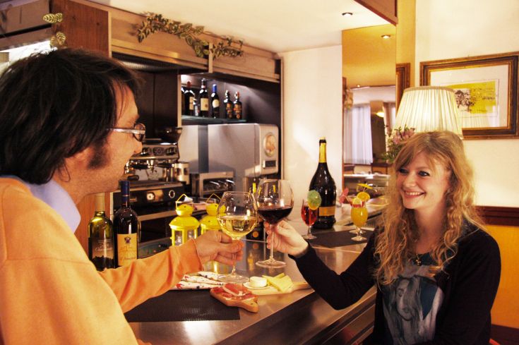 Ein Paar prostet mit Weingläsern in einer eleganten Bar, umgeben von einer angenehmen Atmosphäre.