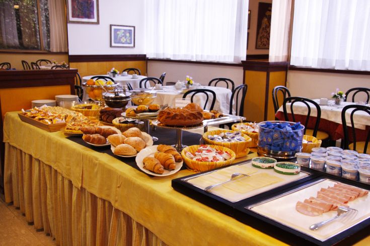 Frühstücksbuffet mit Gebäck, Brot und Wurstwaren, serviert in einem gemütlichen Bereich eines Hotels.