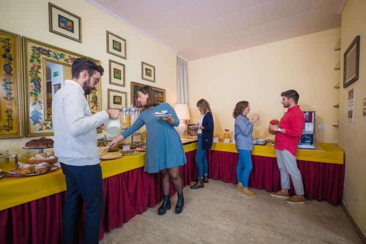 Eine Gruppe von Menschen, die in einer lockeren Atmosphäre frühstückt und von einem üppigen Buffet umgeben ist.
