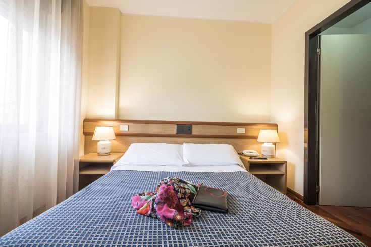 Simple room with a double bed, two lamps, and warm fabrics, perfect for relaxation.