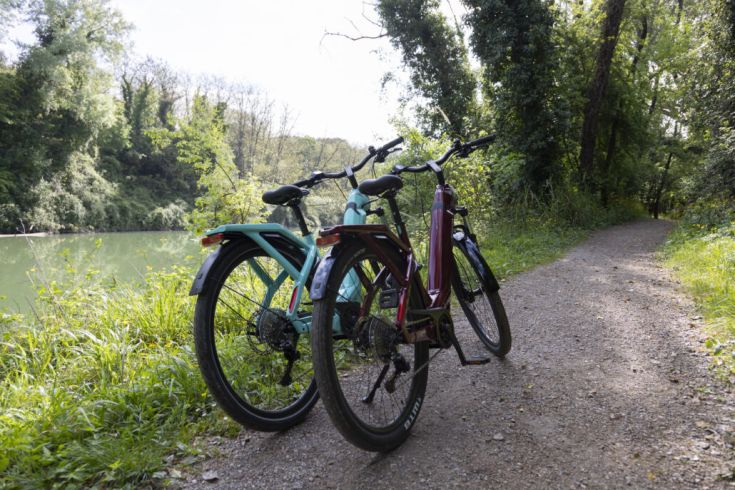 Two bicycles placed on a grassy path beside a serene waterway.