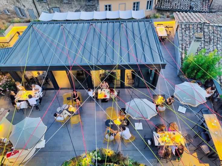 Un rooftop semplice con tavoli, ombrelloni e decorazioni, ideale per cene e aperitivi all'aperto.