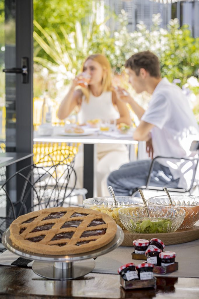Colazione all'aperto con dolci e confetture in un giardino tranquillo, arredato in modo semplice.