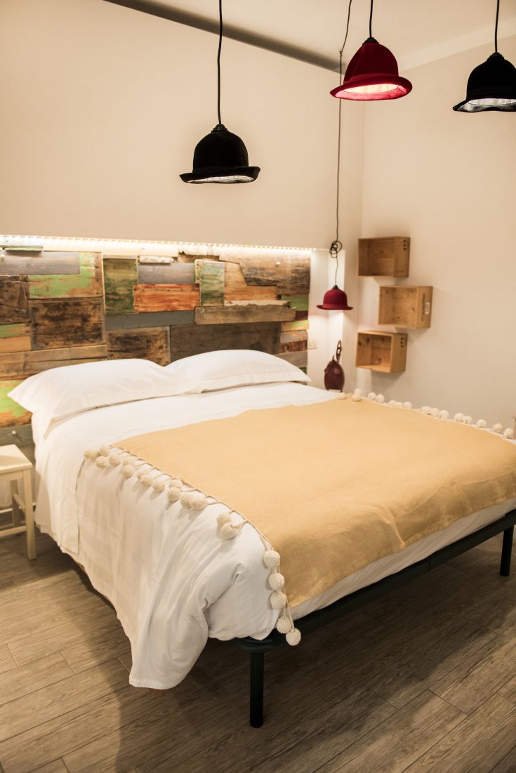 Camera semplice con letto matrimoniale, lampade decorative e pareti in legno con tonalità vivaci.