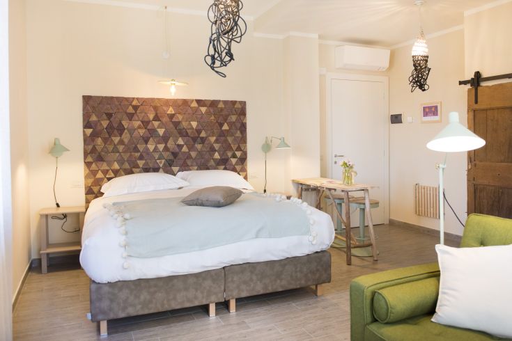 Camera spaziosa con letto matrimoniale, semplici decorazioni e un'area relax.