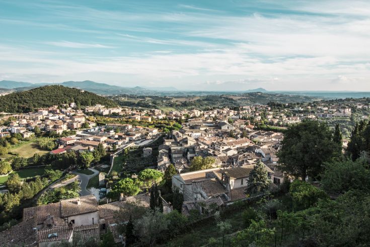 A panoramic view of a peaceful town surrounded by green hills.