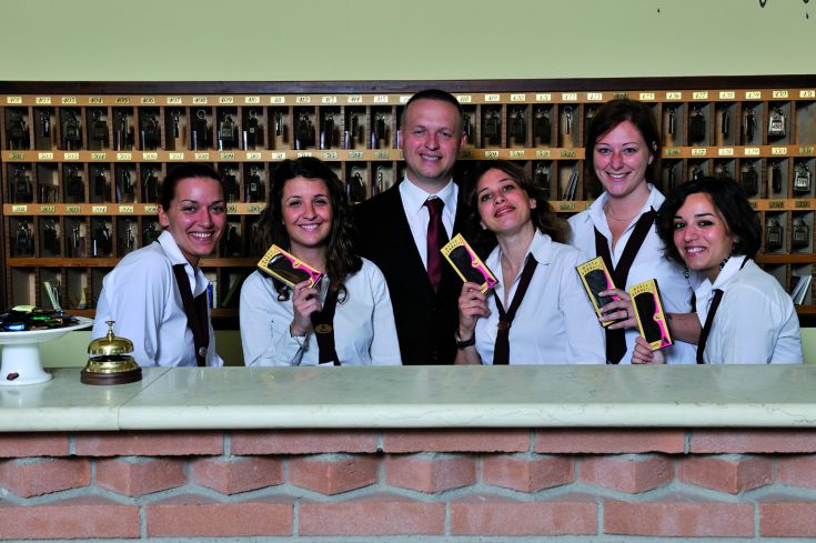 Un groupe de réceptionnistes souriants tenant des clés dans le hall d'un hôtel.