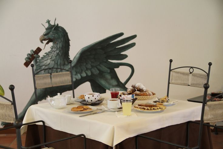 Table dressée pour le petit déjeuner avec des douceurs et des boissons, enrichie d'une fresque de dragon.