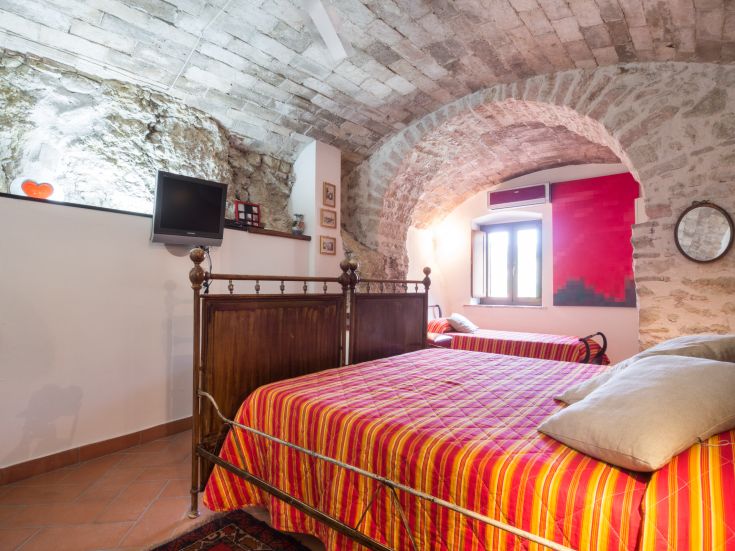 Chambre bien organisée avec plafond voûté et meubles simples, idéale pour un espace de vie relaxant.