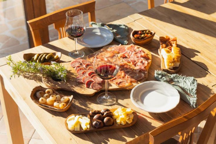 Une table joliment dressée avec des charcuteries et des fromages accompagnés de vin rouge, créant une ambiance chaleureuse.