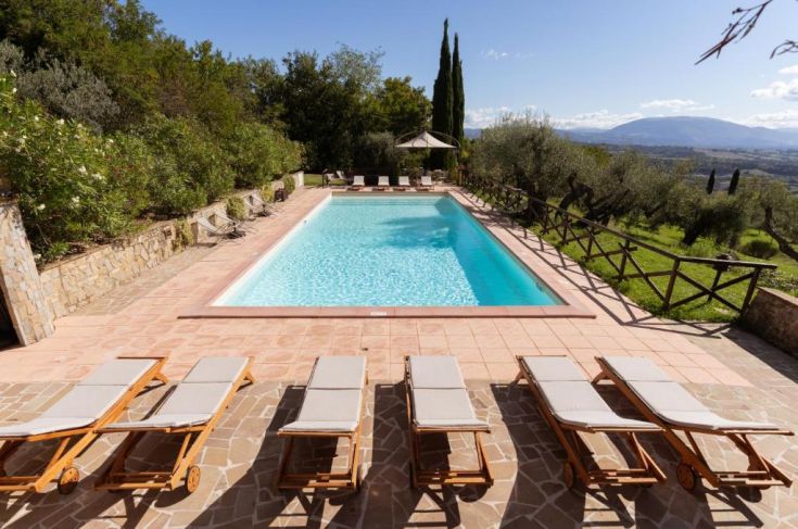 Piscine située dans une ferme en Ombrie, entourée d'arbres et de collines verdoyantes.