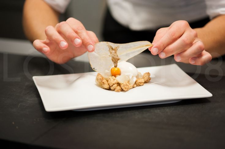 Un cuoco si dedica alla preparazione di un piatto con ingredienti freschi. Un momento di cucina attenta e creativa.