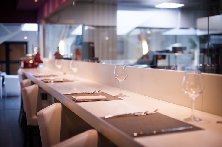 Ristorante contemporaneo con tavoli ben apparecchiati e scena della cucina a vista.