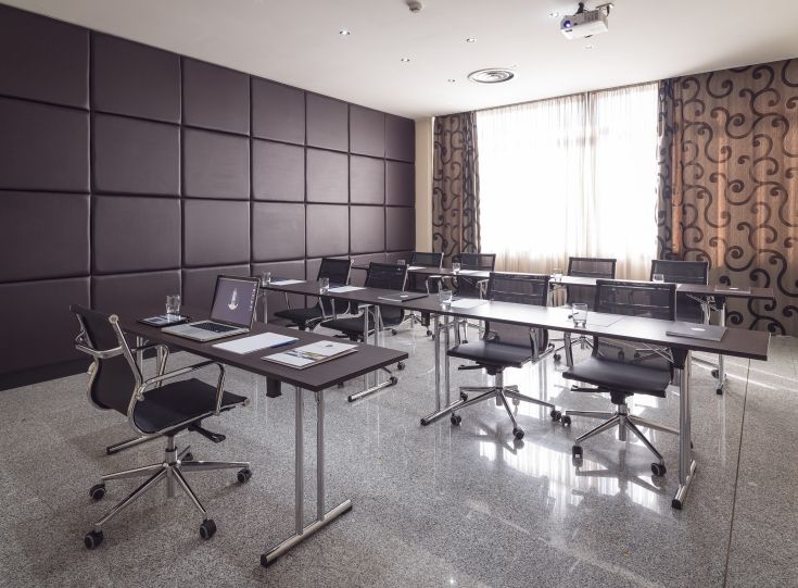 Spazio per incontri caratterizzato da arredi semplici e funzionali, adatto a riunioni di lavoro.