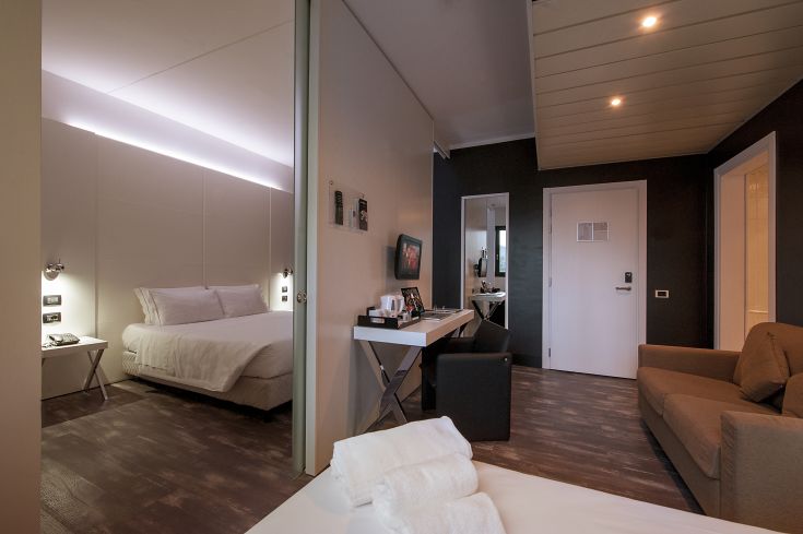 Camera di un hotel contemporaneo, con un letto matrimoniale, un tavolo e una zona salotto ben arredati.