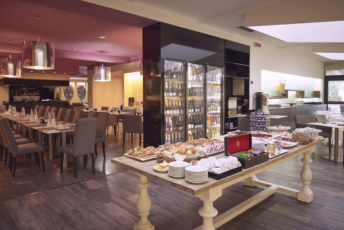 Ristorante moderno con un'area buffet e una selezione di vini, adatto per la colazione. Atmosfera accogliente.